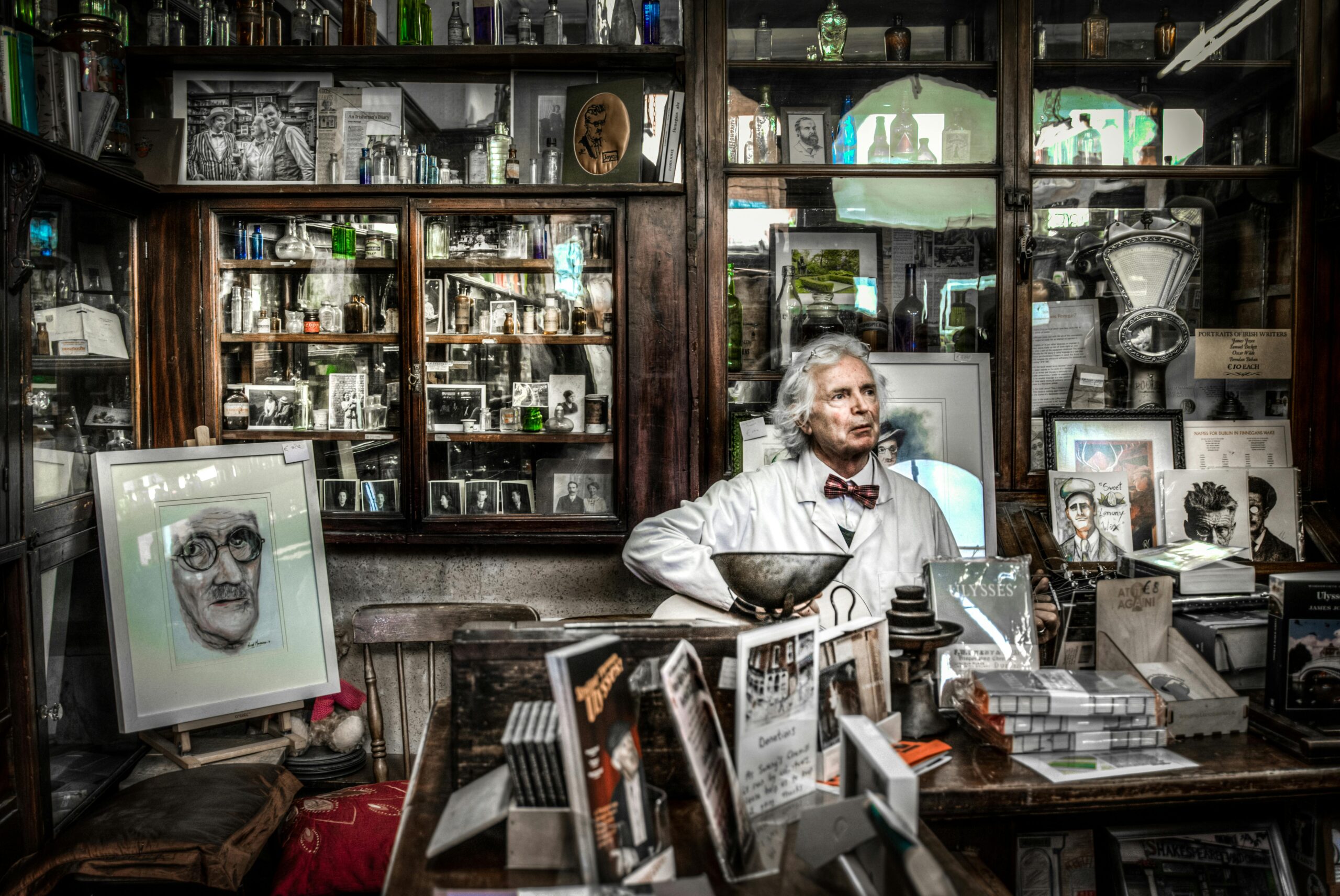 A vintage pharmacy displaying books, portraits, and a pharmacist in a reflective setting.
