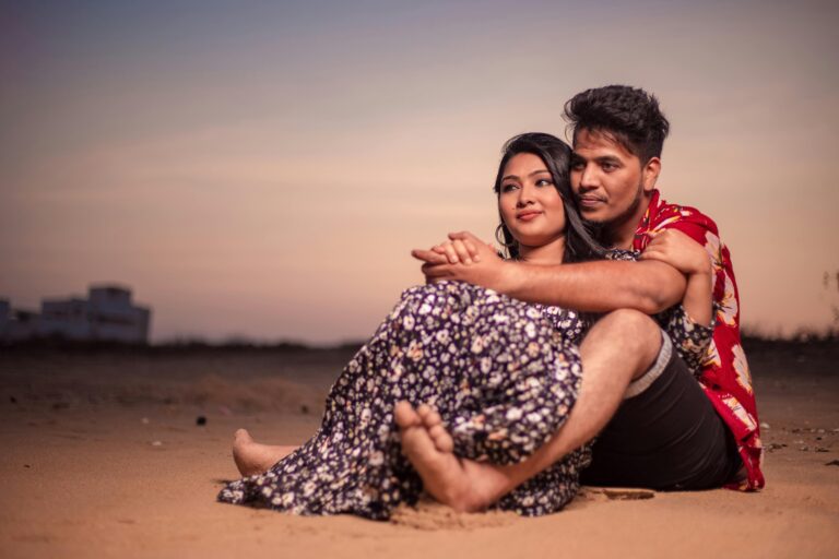 A loving couple embraces on the sandy beach of Chennai, India during a warm sunset.