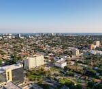 Aerial daytime view of Miami, Florida capturing city skyline and distant ocean.