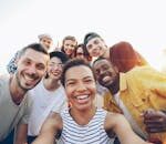 A diverse group of friends taking a joyful selfie outdoors during sunset.