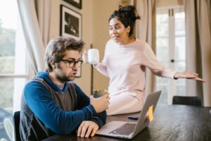 A couple having an argument at home, with a laptop on the table.