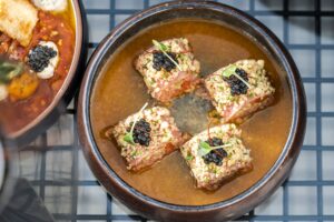 Exquisite crispy beef topped with caviar served in a savory broth, photographed in a Dubai restaurant.
