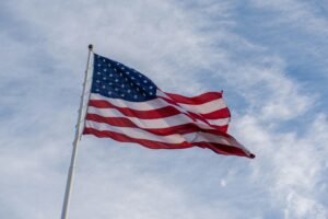 The American flag waves proudly against a backdrop of blue sky, symbolizing freedom and patriotism.