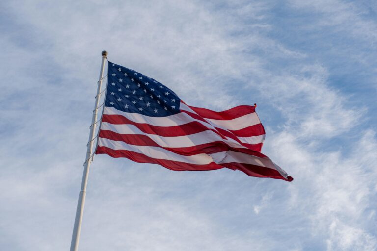 The American flag waves proudly against a backdrop of blue sky, symbolizing freedom and patriotism.