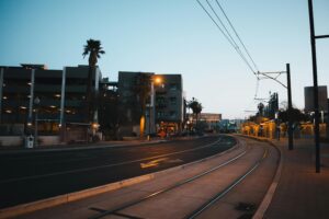 A tranquil evening scene of an empty street with tram tracks and modern buildings.