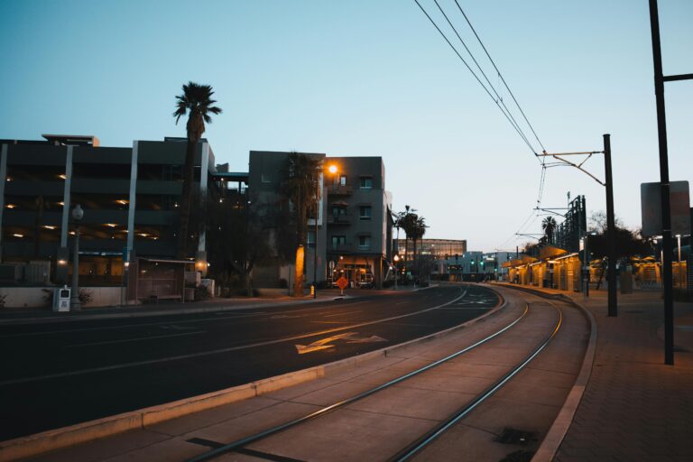 A tranquil evening scene of an empty street with tram tracks and modern buildings.